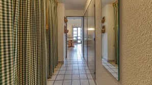 A hallway with checkered curtains, a tiled floor, and a door leading to a room. - Apartment 'Granges 35' with Mountain View and Balcony (Villard-Reculas)