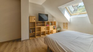 A bedroom with a skylight, a television, wooden shelving, and a bed. - Apartment 'Granges 35' with Mountain View and Balcony (Villard-Reculas)
