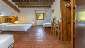 Une chambre avec deux lits, une porte en bois, une fenêtre et un ventilateur.