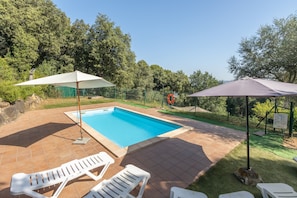 A swimming pool with two white lounge chairs and umbrellas, surrounded by a brick patio and greenery. - Cottage 'Can Ribes' with Outdoor Pool, Garden and Terrace (Camós)