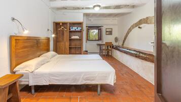 A room with a bed, a wooden wardrobe, a small table, and a window with a view.