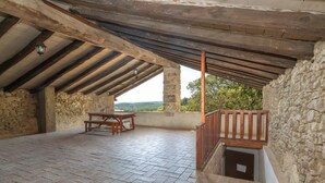 Une terrasse ouverte avec des murs en pierre, une table en bois et une vue sur le paysage.