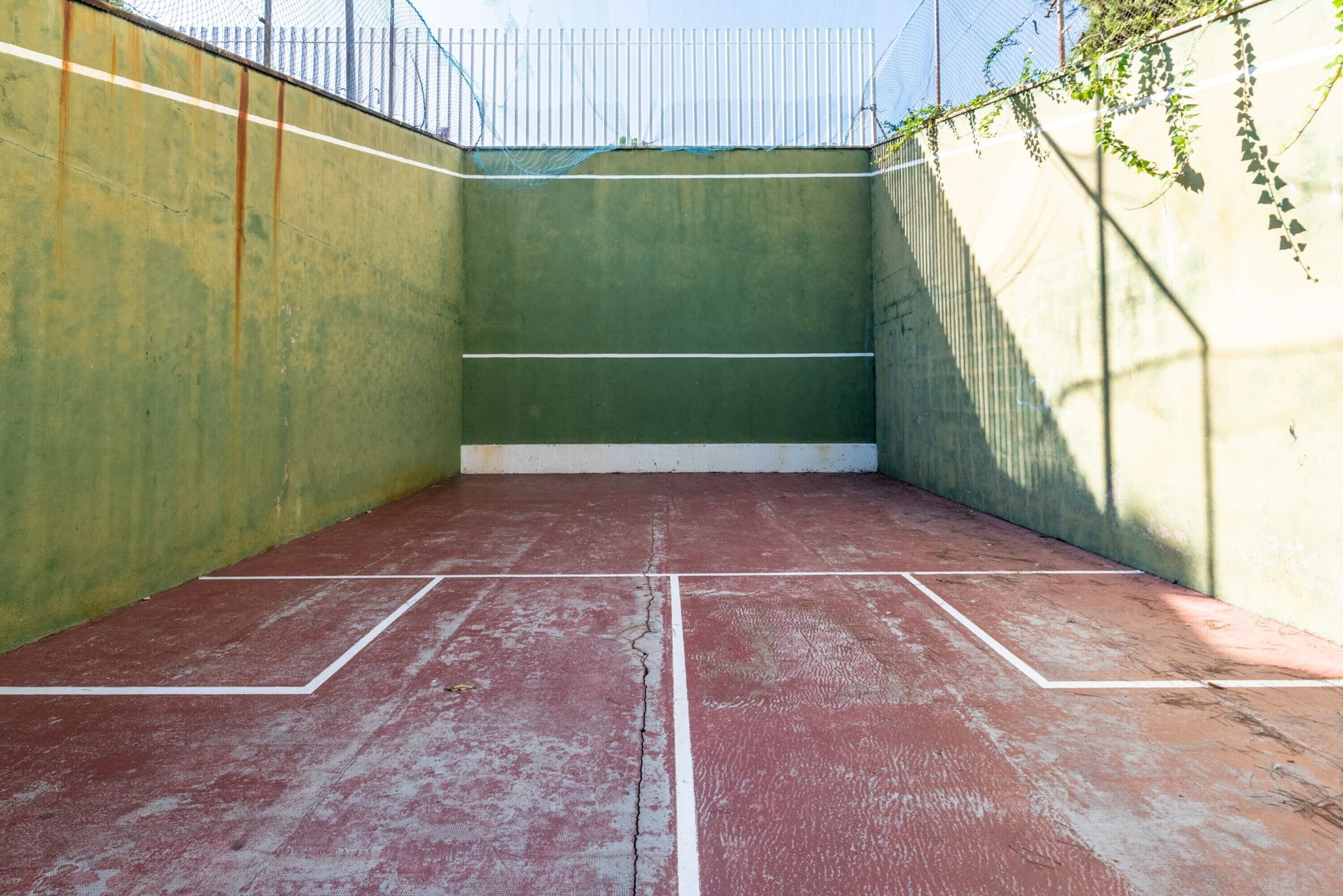 Un court de tennis intérieur avec des murs verts et un sol rouge.