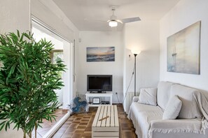 Olohuoneessa on televisio, tuuletin, sohva, sohvapöytä, kattotuuletin ja seinällä taulu.