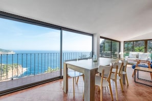Ein geräumiger Balkon mit Blick auf das Meer, ein Esstisch mit Stühlen und eine Sitzecke.