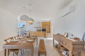 Ein Essbereich mit einem Holztisch, gedeckt für vier Personen, einer Bank und Pendelleuchten.