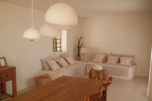 Ein modernes Wohnzimmer mit einem Holzesstisch, einer Sofagarnitur und Pendelleuchten.
