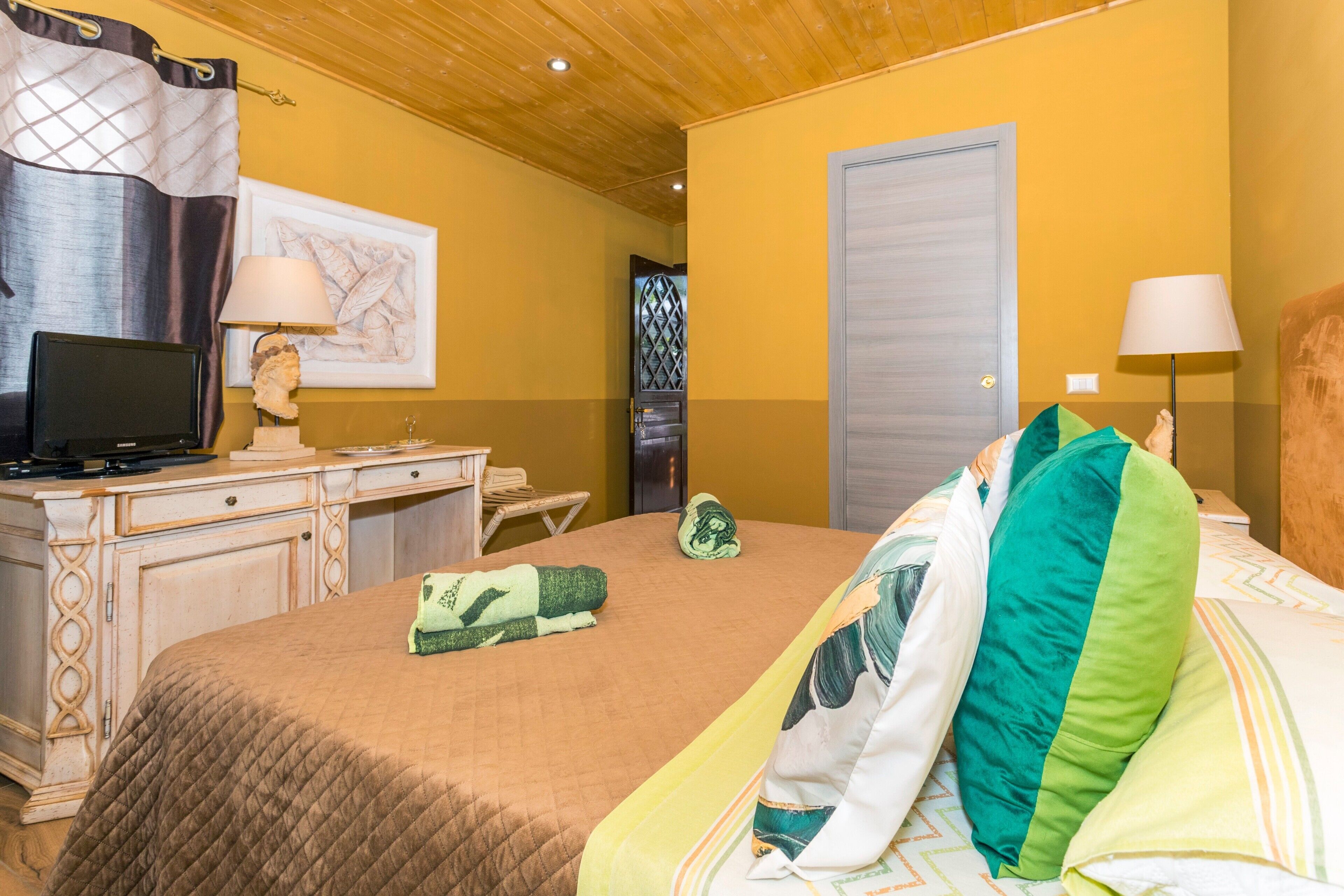 Une chambre à coucher avec un lit, un bureau, une télévision et une porte.