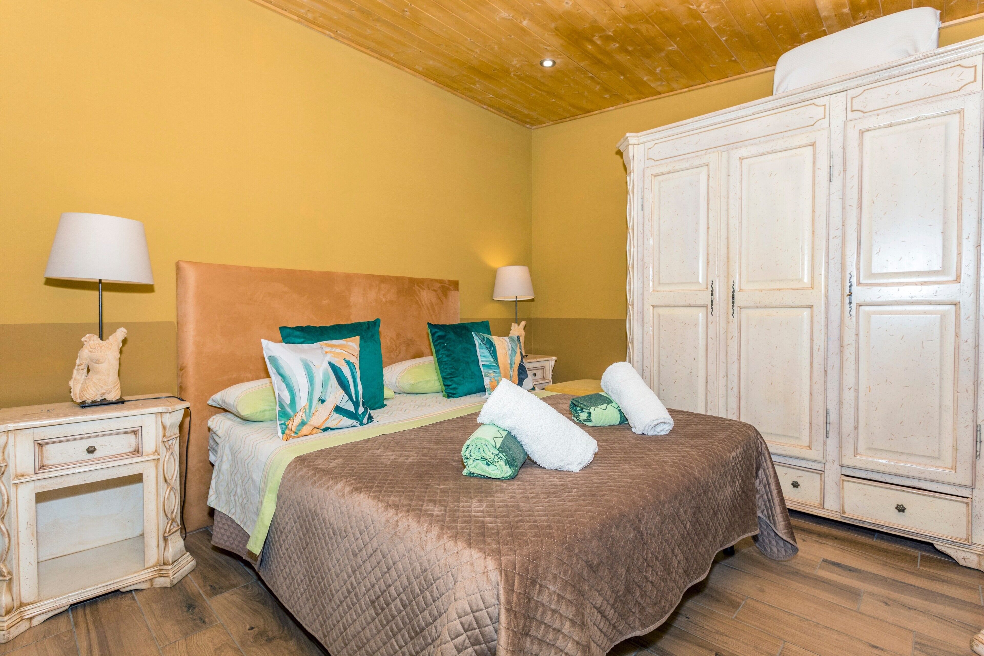 Une chambre à coucher avec un lit, deux tables de chevet, une armoire et une lampe.