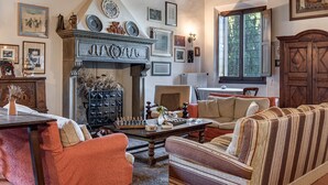 Ein Wohnzimmer mit Kamin, einer Couch, einem Couchtisch und verschiedenen gerahmten Bildern an den Wänden.