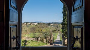 Ein rundbogiger Durchgang mit Blick auf eine ländliche Landschaft, darunter Felder, Bäume und ferne Gebäude.