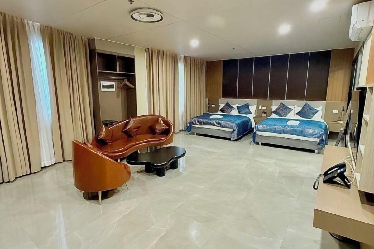 A hotel room with two beds, a sofa, a desk, and a telephone.