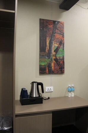 A desk with a kettle, a cup, and two water bottles. - Skyport Hotel (Pasay)