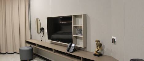 Un salon moderne avec un téléviseur à écran plat, un téléphone, une petite statue et une poubelle.