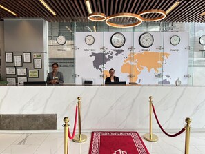 Un comptoir d’accueil avec des horloges indiquant l’heure à Berlin, New York, Londres, Manille et Tokyo.
