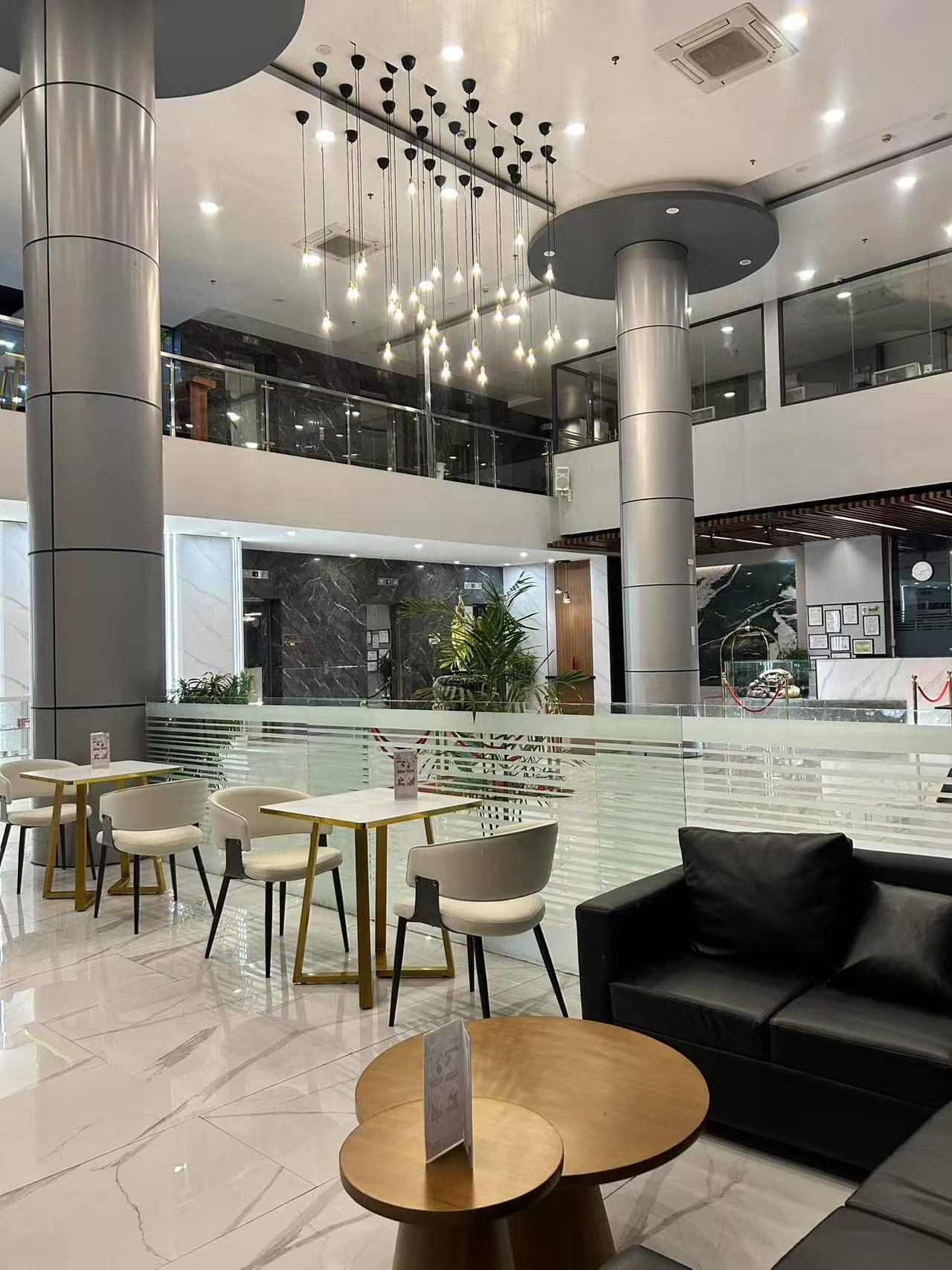 A modern indoor space with a central water feature, seating areas, and a mezzanine level.