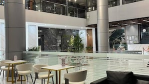 Un espace intérieur moderne doté d’un élément aquatique central, de coins salon et d’une mezzanine.