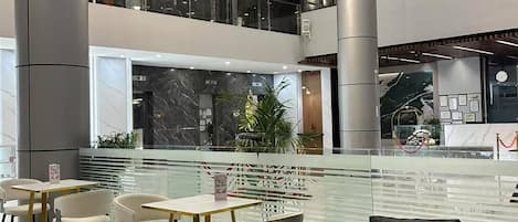 A modern indoor space with a central water feature, seating areas, and a mezzanine level.