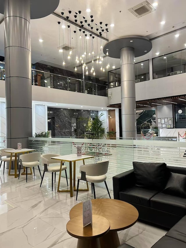 A modern indoor space with a central water feature, seating areas, and a mezzanine level. - Skyport Hotel (Pasay)