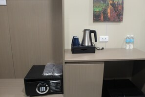Habitación de hotel con un escritorio de madera, una tetera, dos botellas de agua y una caja con candado.