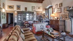 A spacious living room with a high wooden ceiling, a fireplace, and a dining area with a table and chairs.