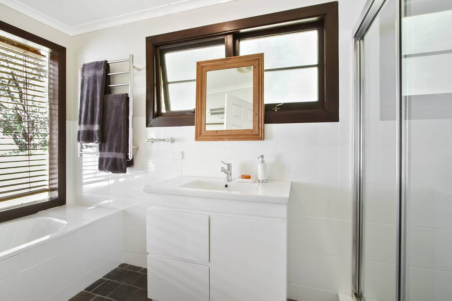 Un baño moderno con bañera, lavamanos con espejo y zona de ducha.