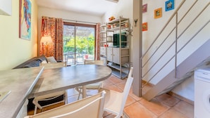 Un espacio comedor con mesa y sillas, un sofá, un televisor, una escalera y una lavadora.