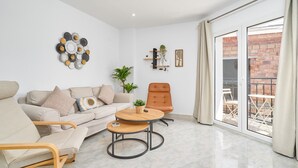 A modern living room with a sofa, armchairs, a coffee table, and a sliding glass door leading to an outdoor area.