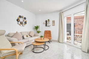 A modern living room with a sofa, armchairs, a coffee table, and a sliding glass door leading to an outdoor area.