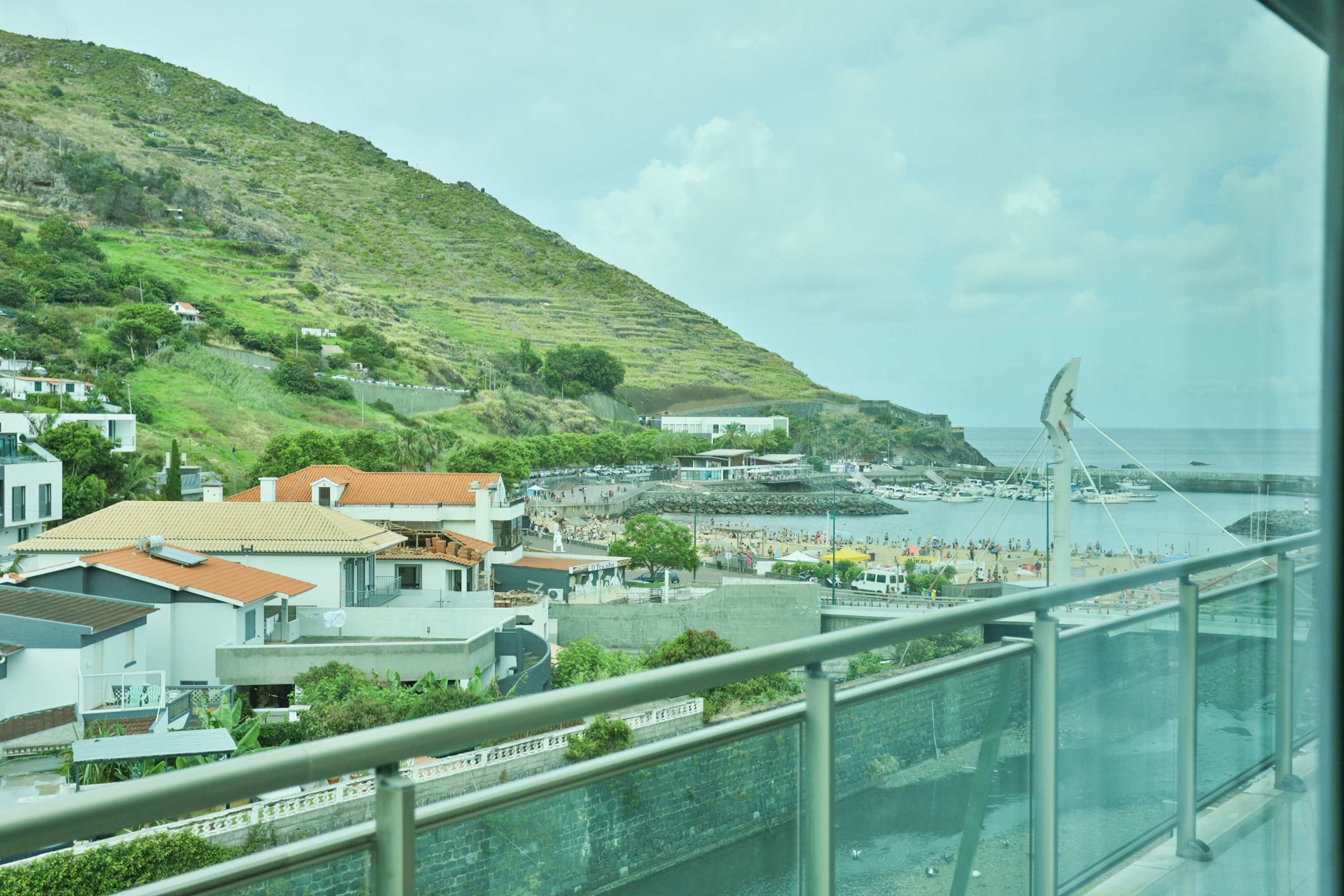 A coastal town with buildings, a hill, and a view of the sea.