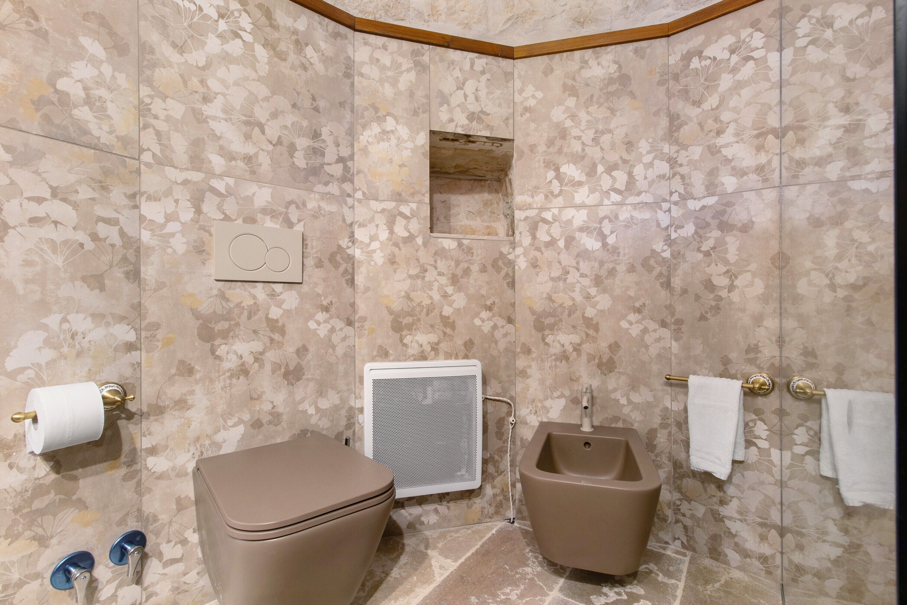 A bathroom with a toilet, bidet, towel rack, and a shower enclosure.