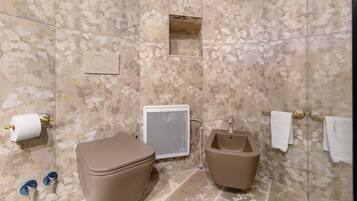 A bathroom with a toilet, bidet, towel rack, and a shower enclosure.