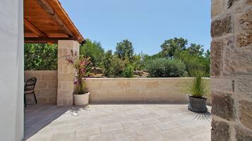 Un patio con piso de piedra, una pérgola de madera y plantas en macetas.