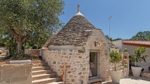 Un bâtiment en pierre avec un toit recouvert de tuiles, une petite porte et des marches menant à l’entrée.