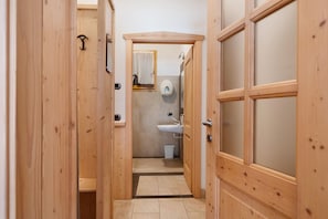A narrow hallway with wooden doors, a small window, and a sink.