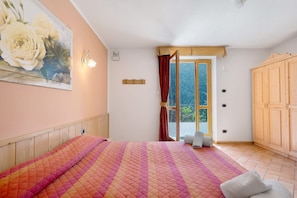 Une chambre à coucher avec un lit, un tableau, une fenêtre avec des rideaux et une armoire en bois.