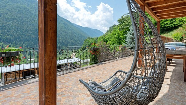 Una poltrona sospesa su un patio in pietra con vista sulle montagne.