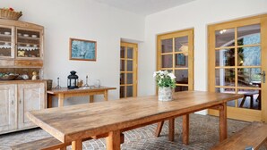 Un tavolo da pranzo in legno con panche, un mobile con ante in vetro e un quadro appeso al muro.