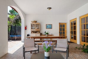 Une terrasse avec une table, des chaises, un meuble et une porte.