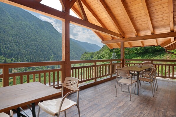 Une terrasse en bois, agrémentée de tables et de chaises, qui offre une vue sur un paysage montagneux.