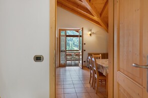 A wooden interior with a dining area, a small window, and a door leading outside.