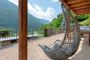 A hanging chair on a stone patio with a mountain view. - Room 'Stanza 2' with Mountain View, Private Terrace and Wi-Fi (Caldes)