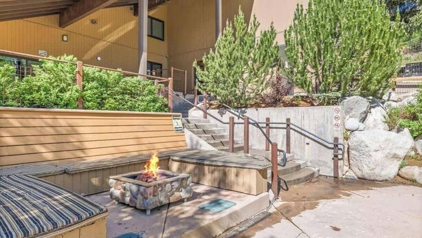 Un foyer extérieur avec un banc, un escalier et un bâtiment à l’extérieur en bois.