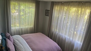 A bedroom with a bed, curtains, and a window with a view of trees. - Where comfort meets the mountains—close to everything,spacious,and pet-friendly! (Cromwell)