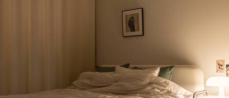 Una habitación de hotel con una cama, una mesita de noche con una lámpara y un cuadro en la pared.