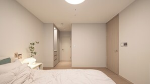 Une chambre à coucher avec un lit, une table de chevet, une lampe et une plante.