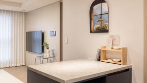 Une cuisine moderne dotée d’un plan de travail en granit, d’un four encastré et d’une fenêtre donnant sur un jardin fleuri.