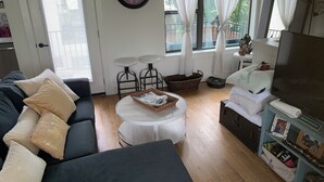 A living room with a sofa, a coffee table, a clock, a TV, and a bookshelf.