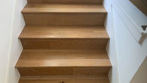 A wooden staircase with white walls and a white baseboard.