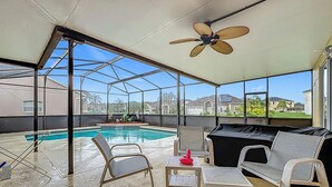 Un espacio al aire libre techado con piscina, mobiliario y ventilador de techo.